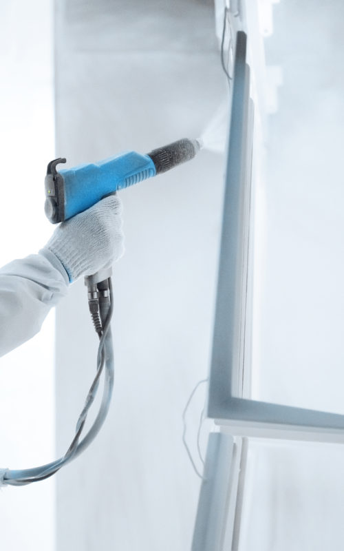 Hand of a worker in a protective work wear holding powder coating sprayer in a metal producing factory