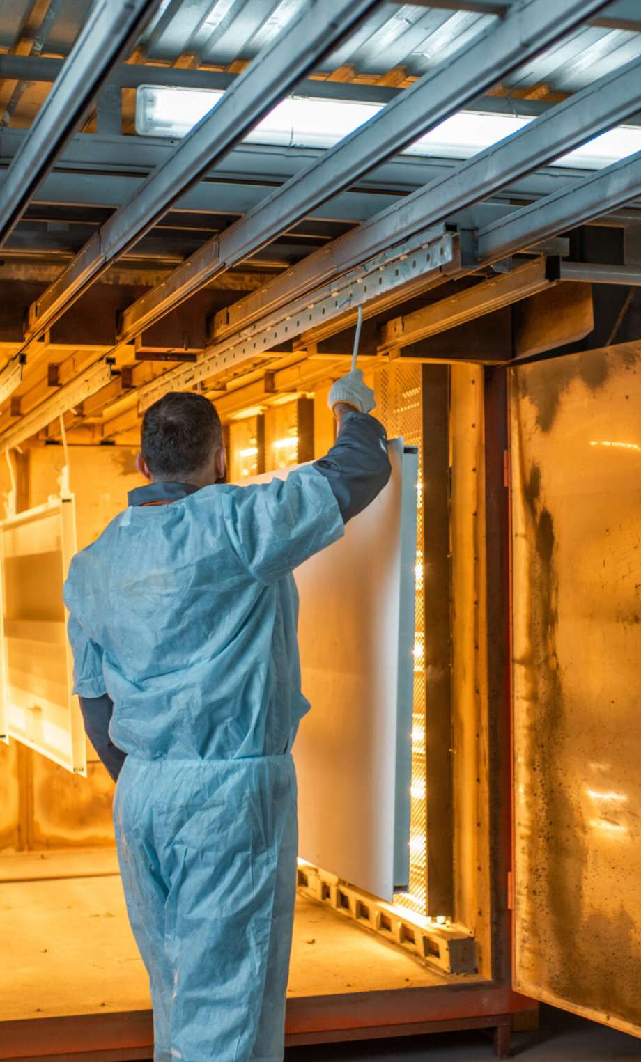 Worker of the painting shop pushing metal products into the oven for baking powder paint. Powder coating process at the manufacturing. High quality photo